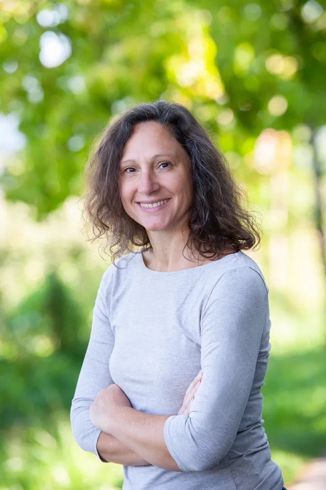 Valeska Otto lächelt im Freien vor einem grünen Naturhintergrund